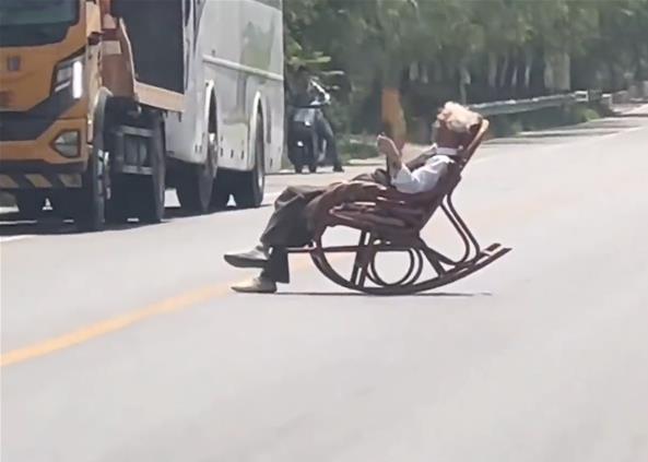 大爷躺马路中间晒太阳 车辆纷纷避让